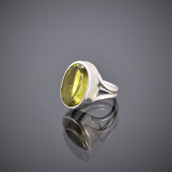 Side view of chunky oval peridot and silver wire ring. Peridot set in rubover setting