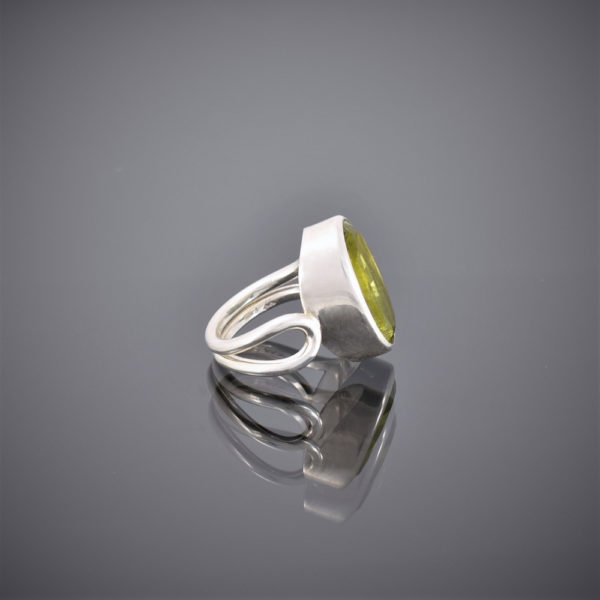 Side view of chunky oval peridot and silver wire ring. Peridot set in rubover setting.