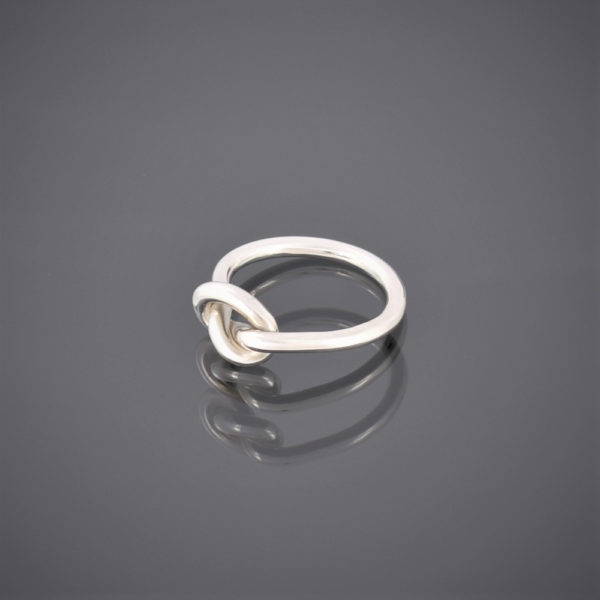 Side view of a solid silver wire ring formed in a knot to represent friendship