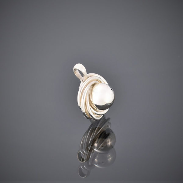 Side view of a solid silver pendant made of a silver ball surrounded by silver wire swirls