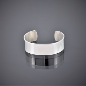 Flat view of a wide solid silver cuff polished to a high shine
