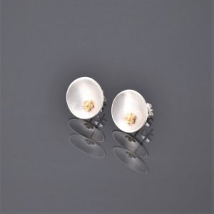 Side view of concavec brushed silver stud earrings with 22ct yellow gold flower detail.
