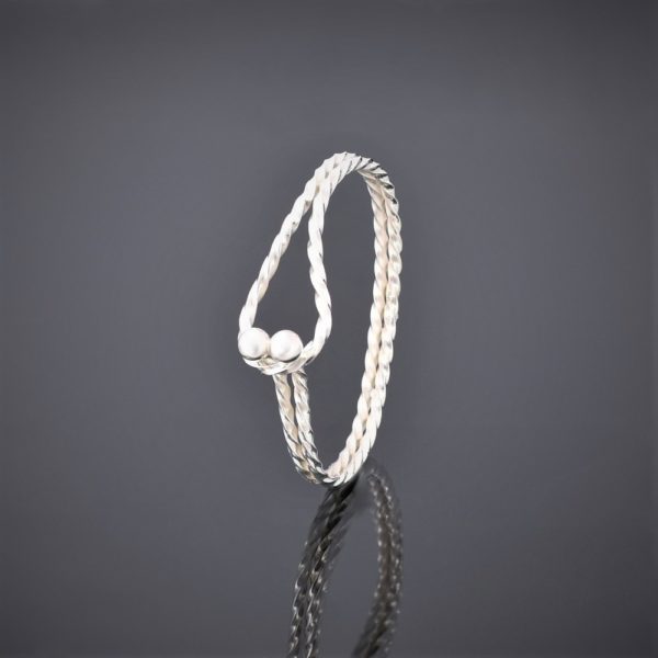 Upright left view of a twisted solid silver square wire bangle with tension clasp