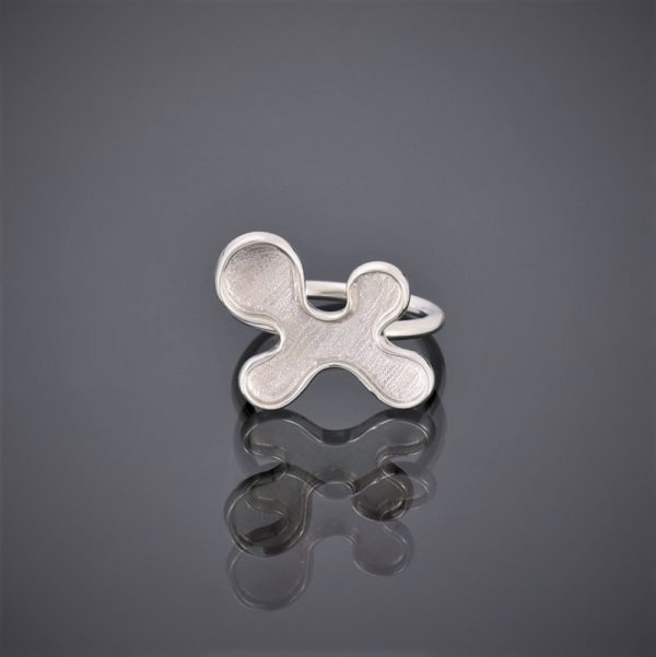 Front view of a silver puzzle piece shaped ring. The ring has a mat finish with round silver wire shank.