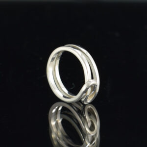 Upright view of a square solid silver wire infinity ring on black background